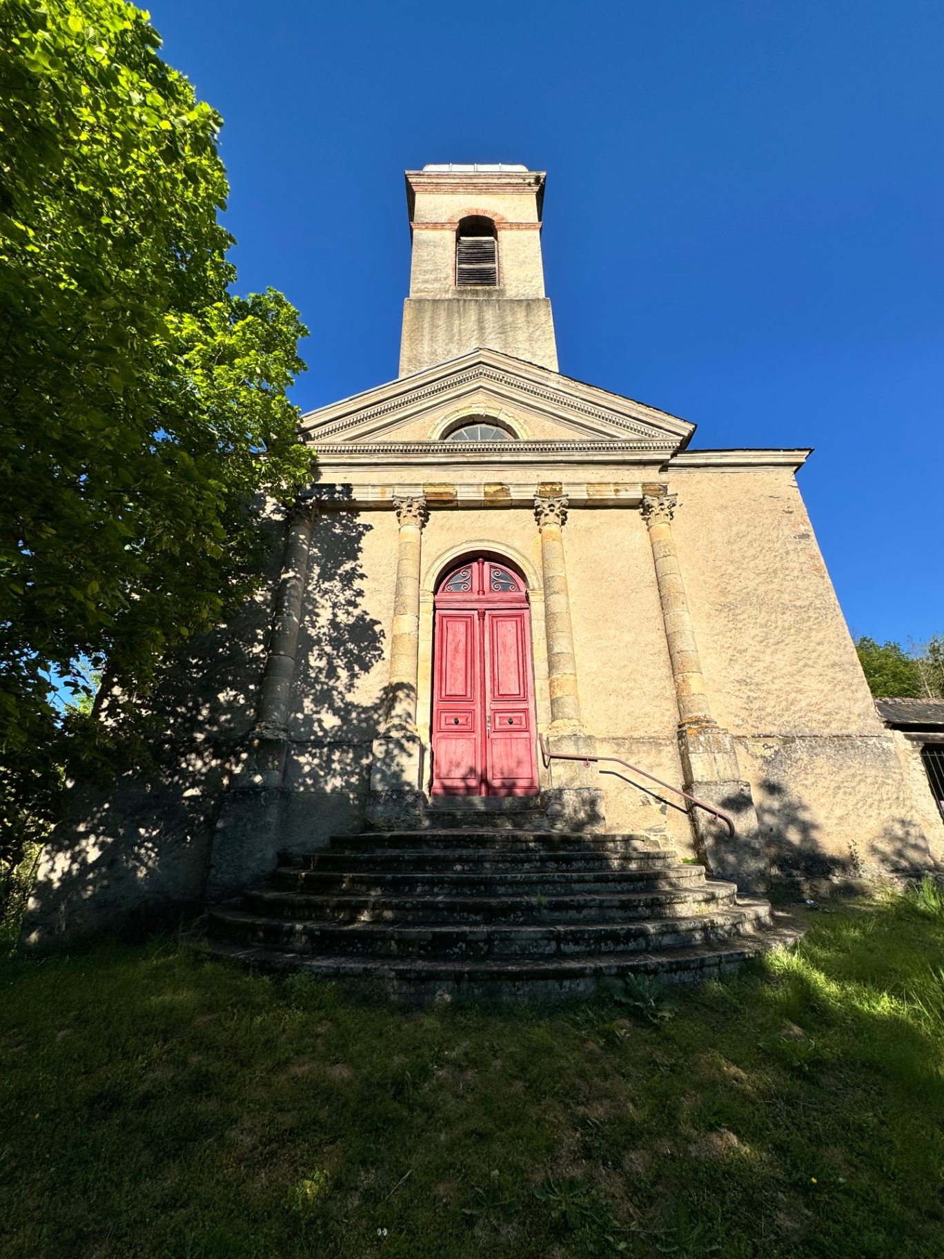Façade de l'église Notre-Dame de Bonneval, portail rouge et clocher